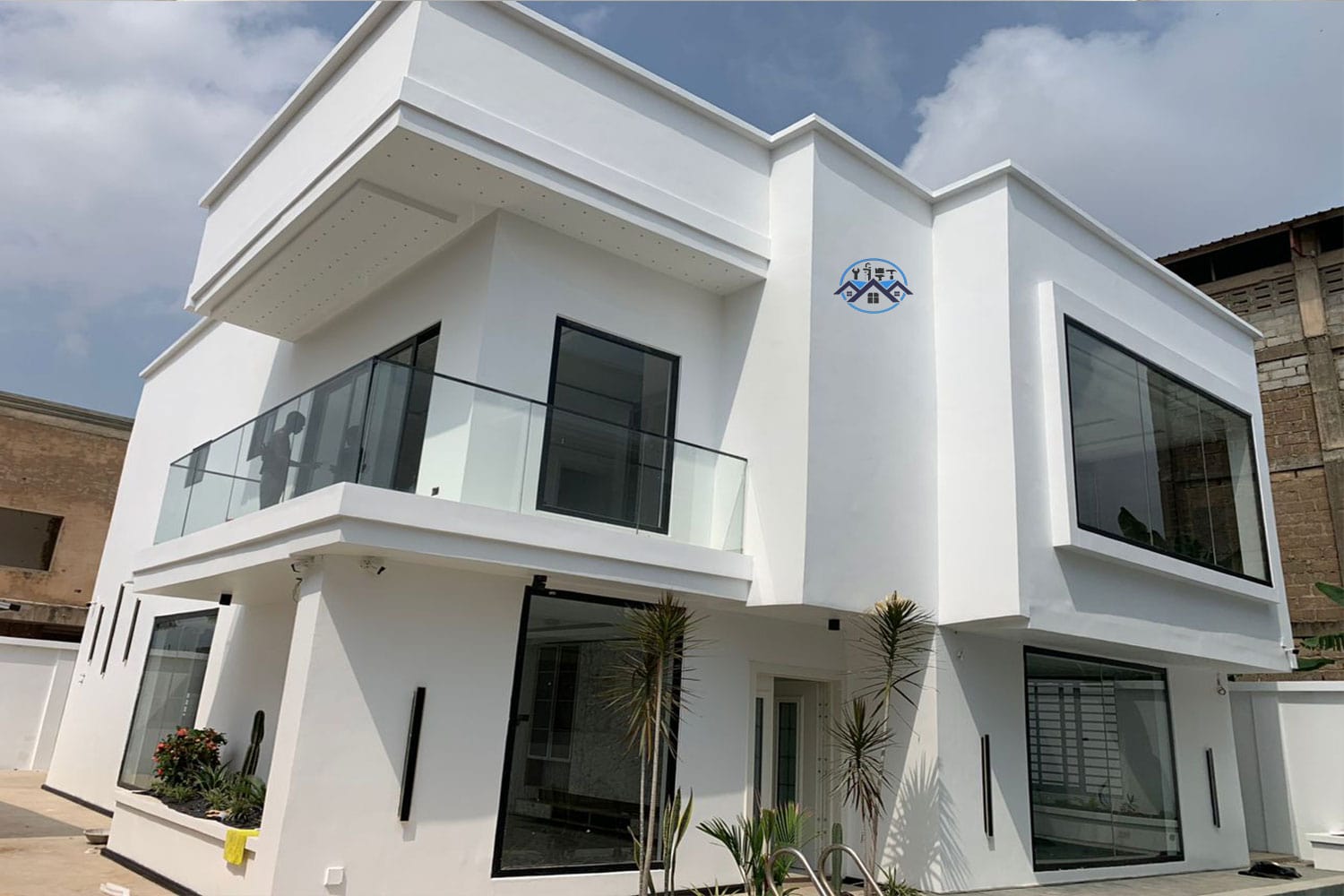 Professional painter applying smooth finish to an exterior wall of a modern house in Accra, Ghana – Waterworld Technology Limited painting service.